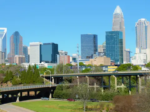 Charlotte skyline above the trees and the greenway bridge