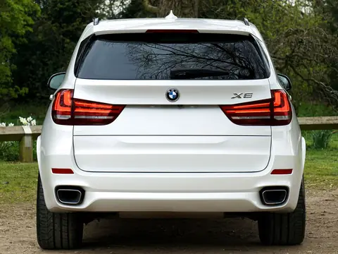 Rear glass of a white SUV parked by a lawn