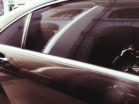 Reflections across the side windows of a dark sedan
